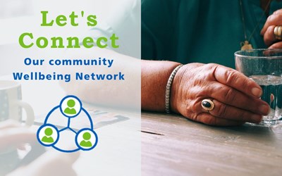 Image shows the hands of a person sitting at a table across from another person. The hands are holding a glass of water. There is text over the image that says Let's Connect Our Community Wellbeing Network