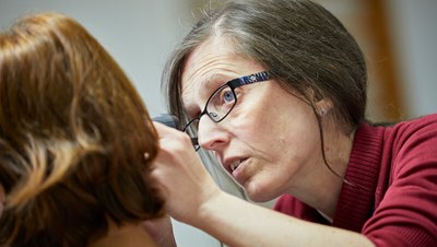 A hearing specialist checking a patient's ear