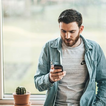 Young man looking at his phone in a light, airy room