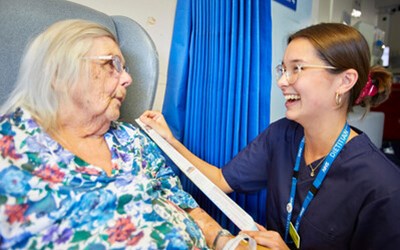 A staff member talking to a patient bedside