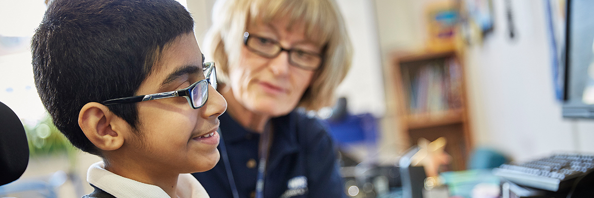 Male student at computer with helper